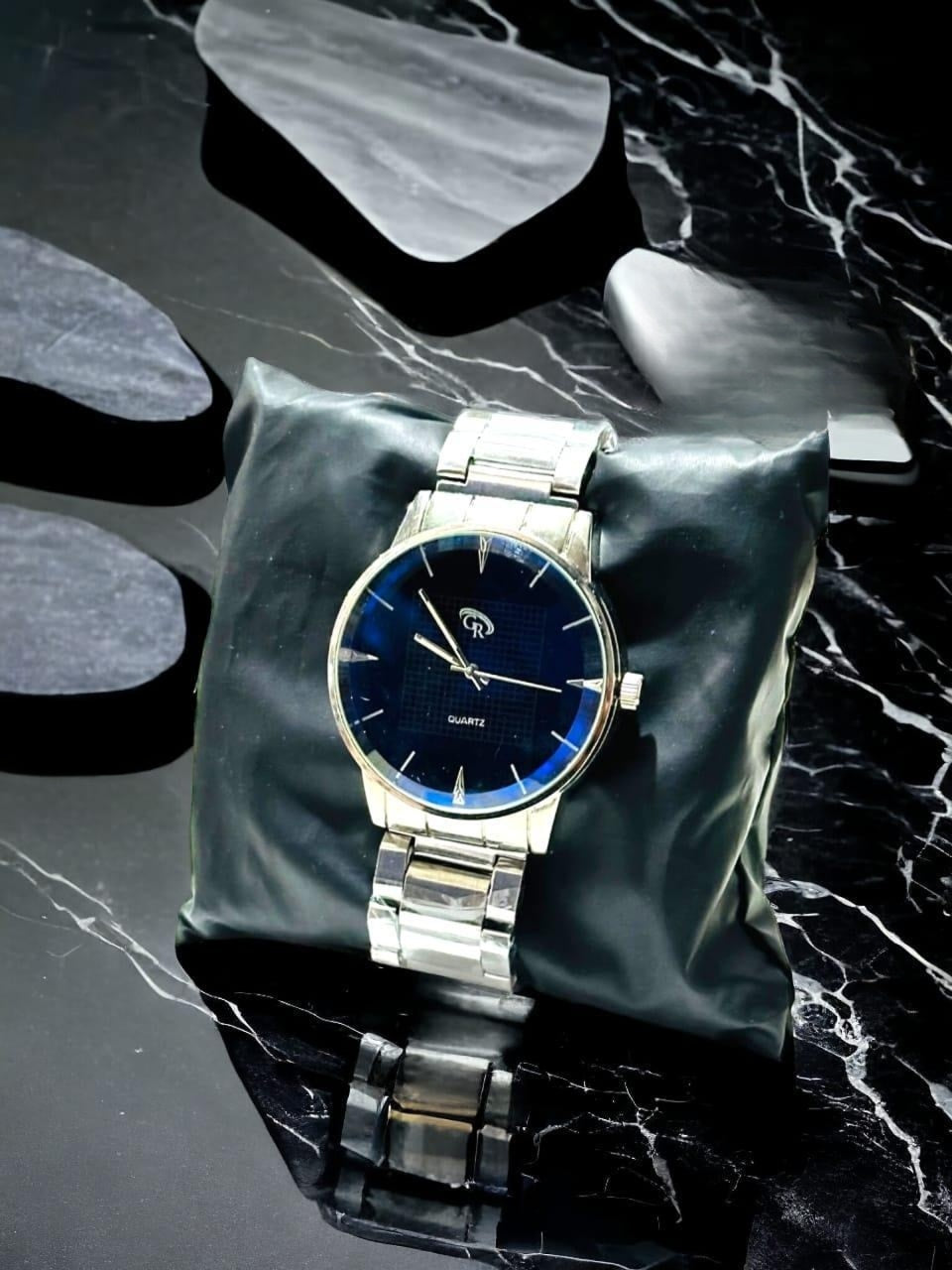 Silver watch with a blue face on a dark marble surface